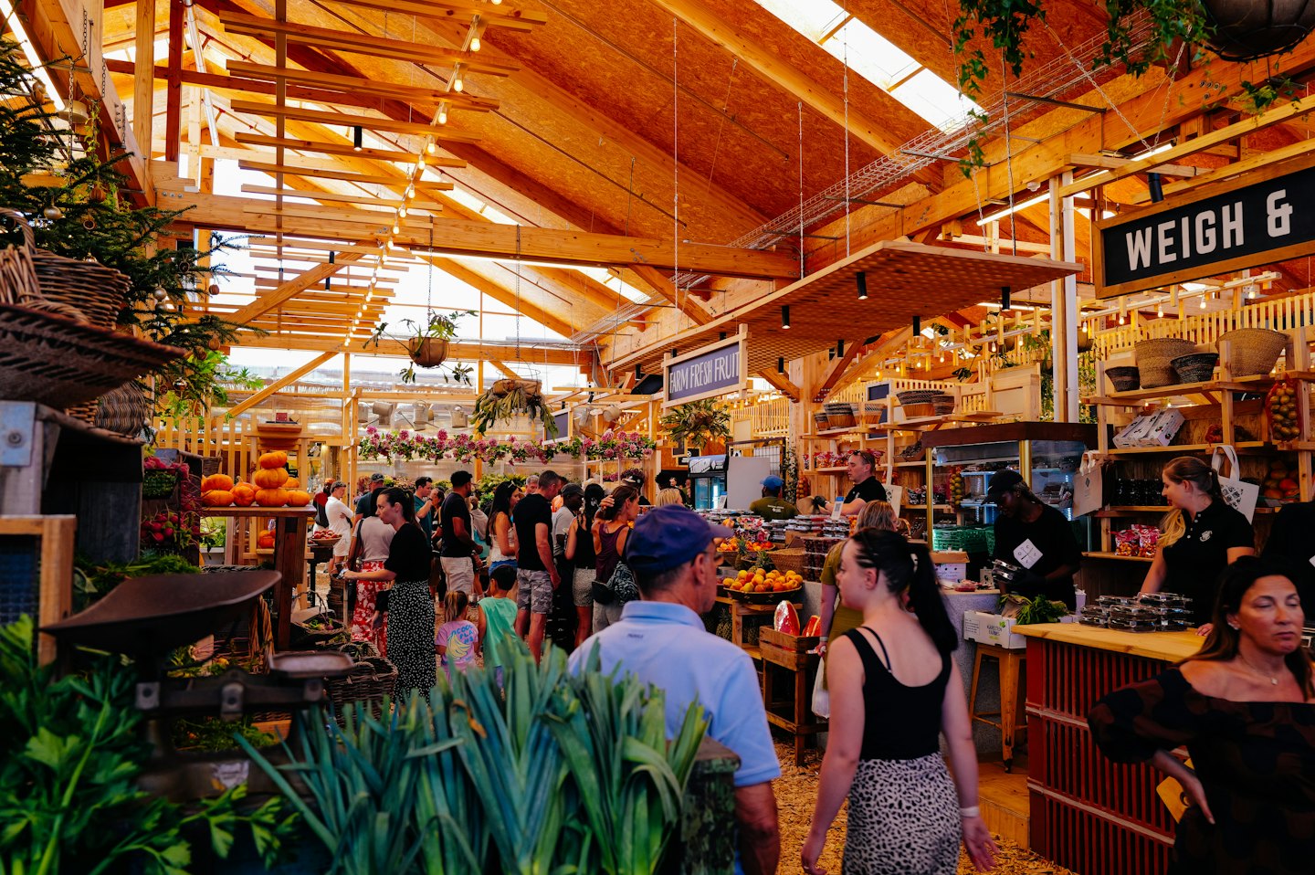 People shop for fresh produce at a bustling indoor market.