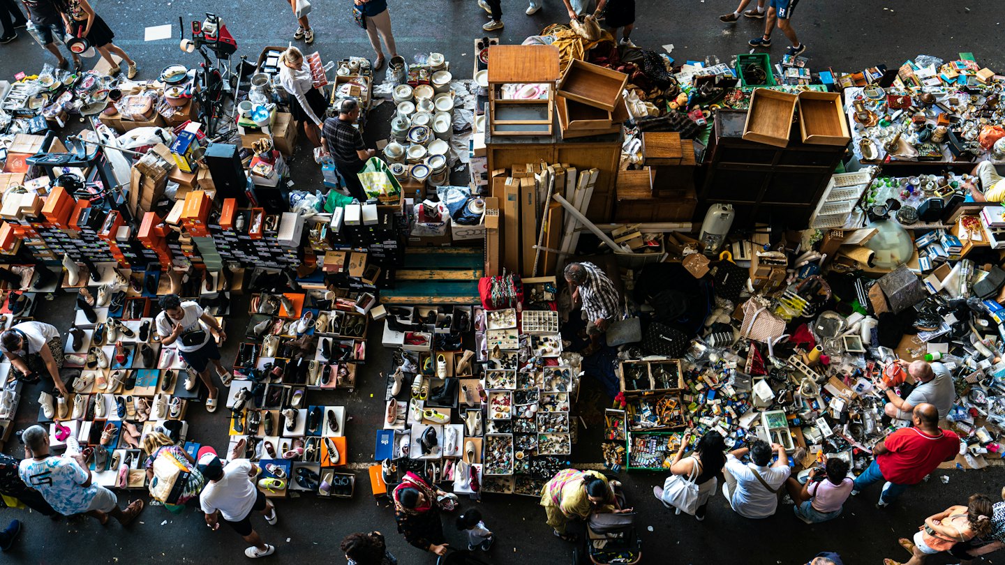 Shoppers browse through diverse items at an outdoor market.