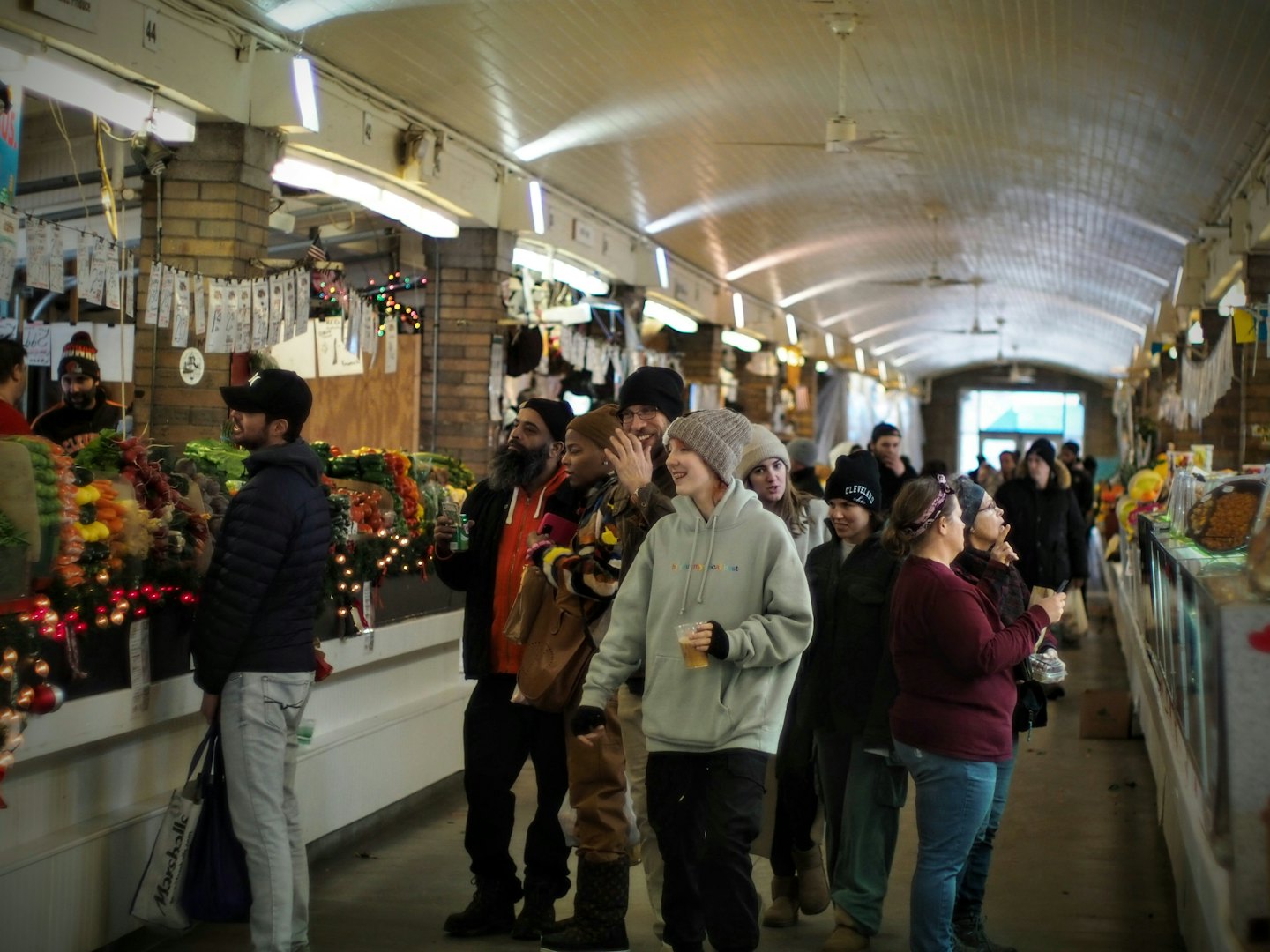 People browse stalls in a festive indoor market hall.