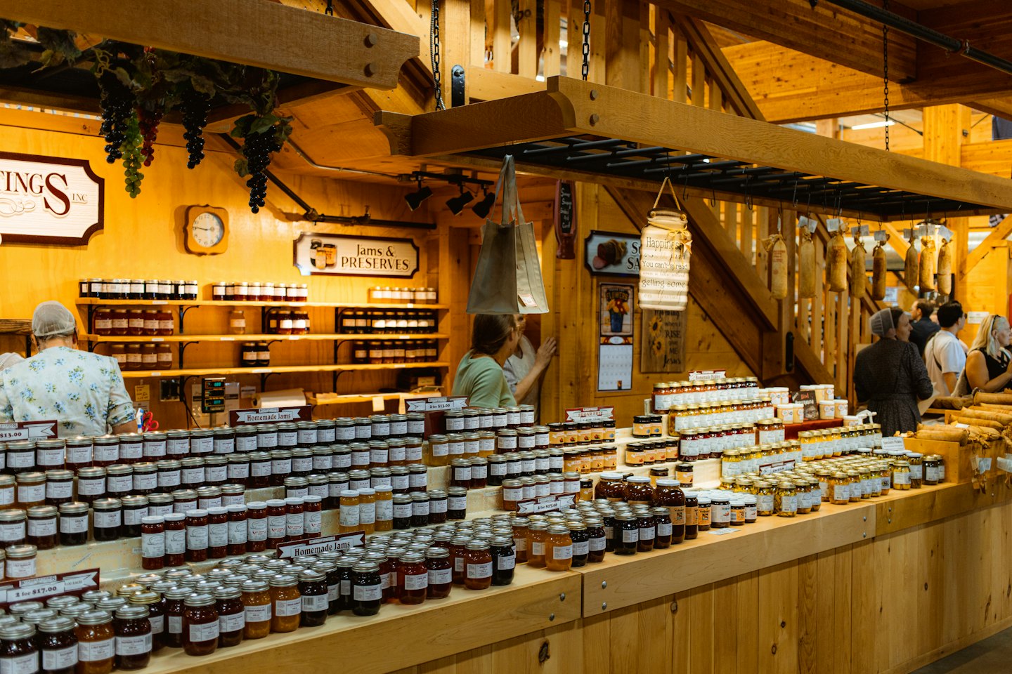 Shoppers browse rows of glass jars at a rustic market.