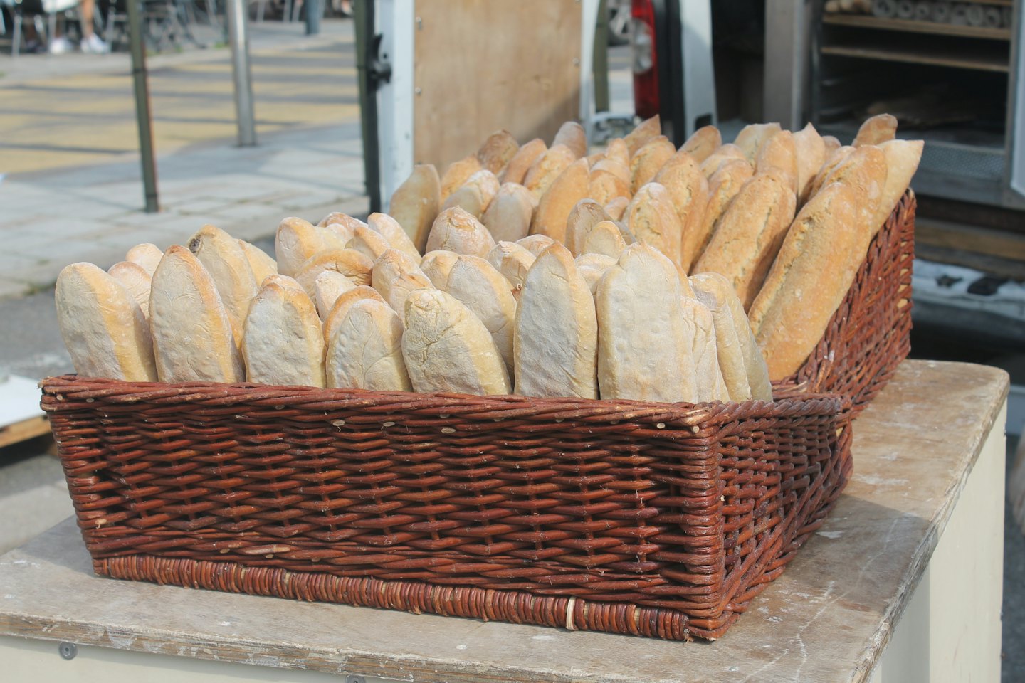 Two woven baskets overflow with freshly baked crusty bread loaves.